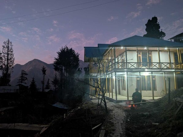 A two-story building with a glass facade, surrounded by trees and mountains. - Shangarh JC Snow Valley (Shangarh)