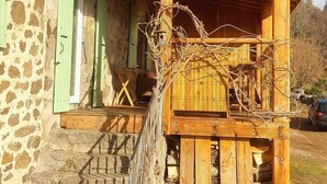Ein Steinhaus mit einem Holzbalkon und einer Treppe zum Eingang.