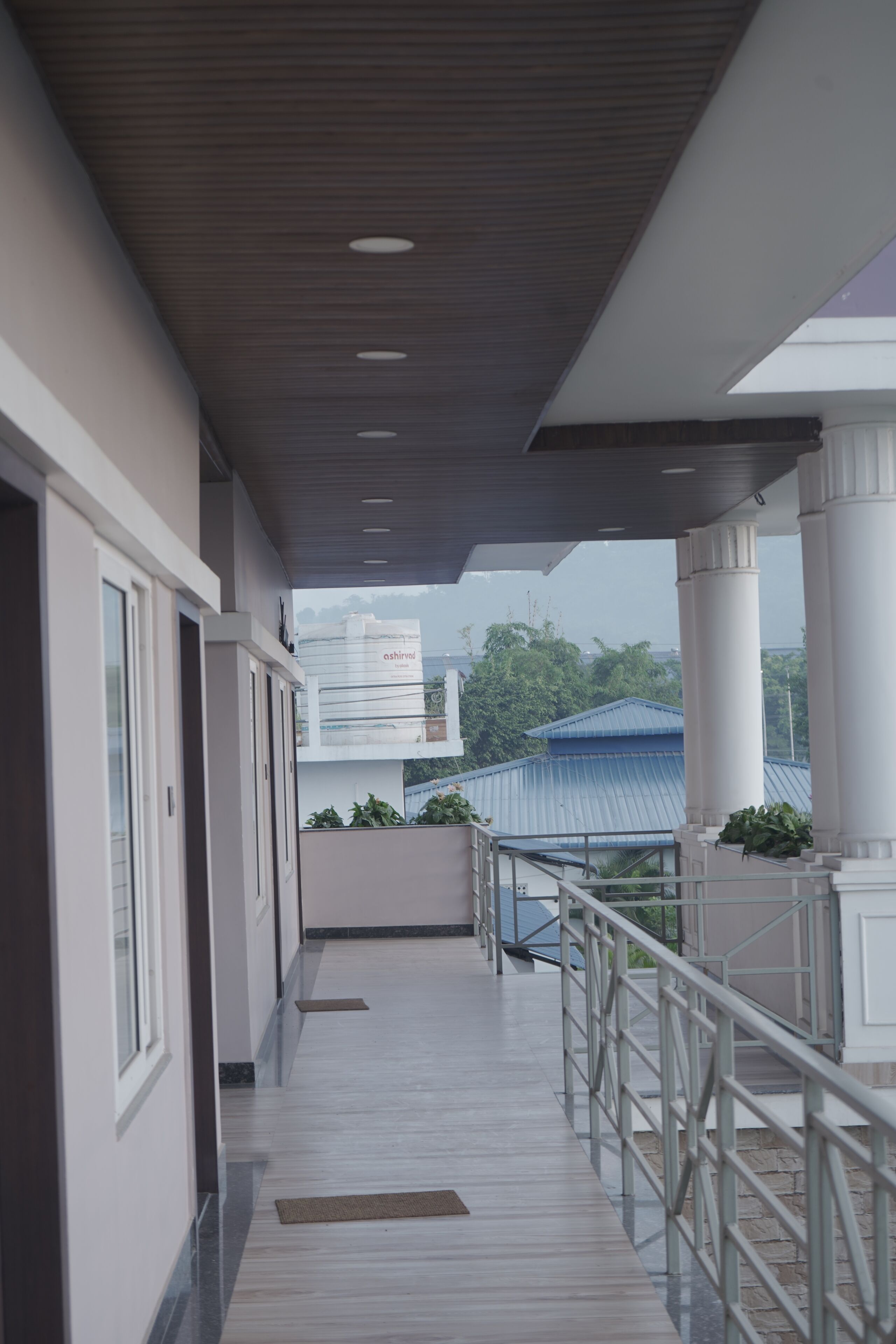 A corridor with a wooden ceiling, white walls, and a metal railing.