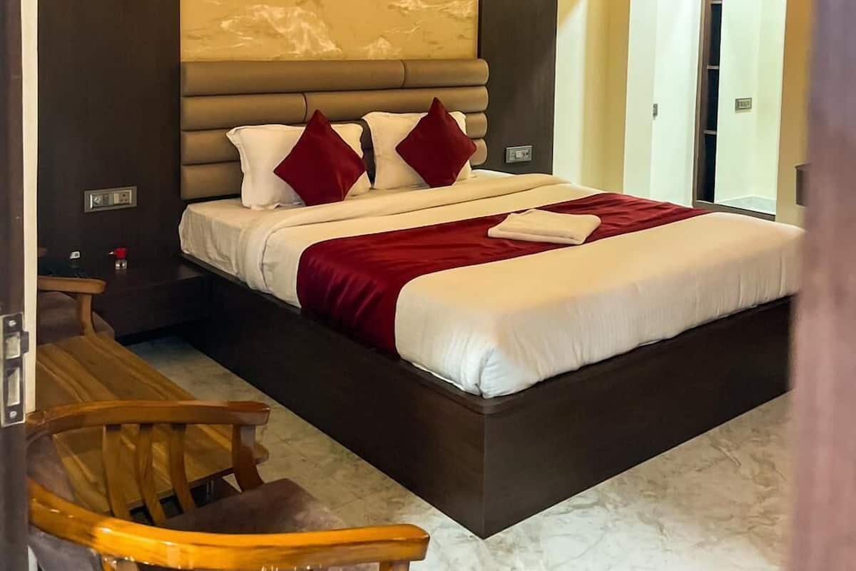 A modern hotel room with a large bed, a wooden chair, a desk, and a view of the outside.