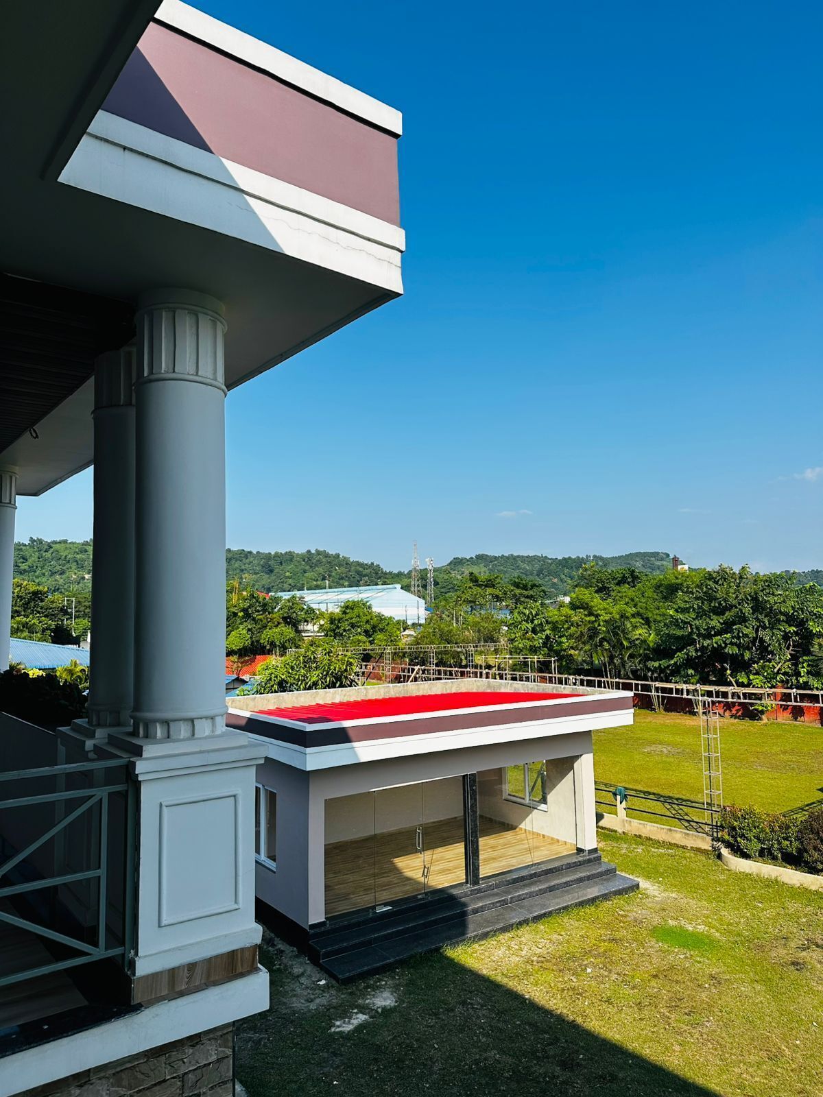 A modern building with a flat roof, large columns, and a covered area with steps leading up to it.