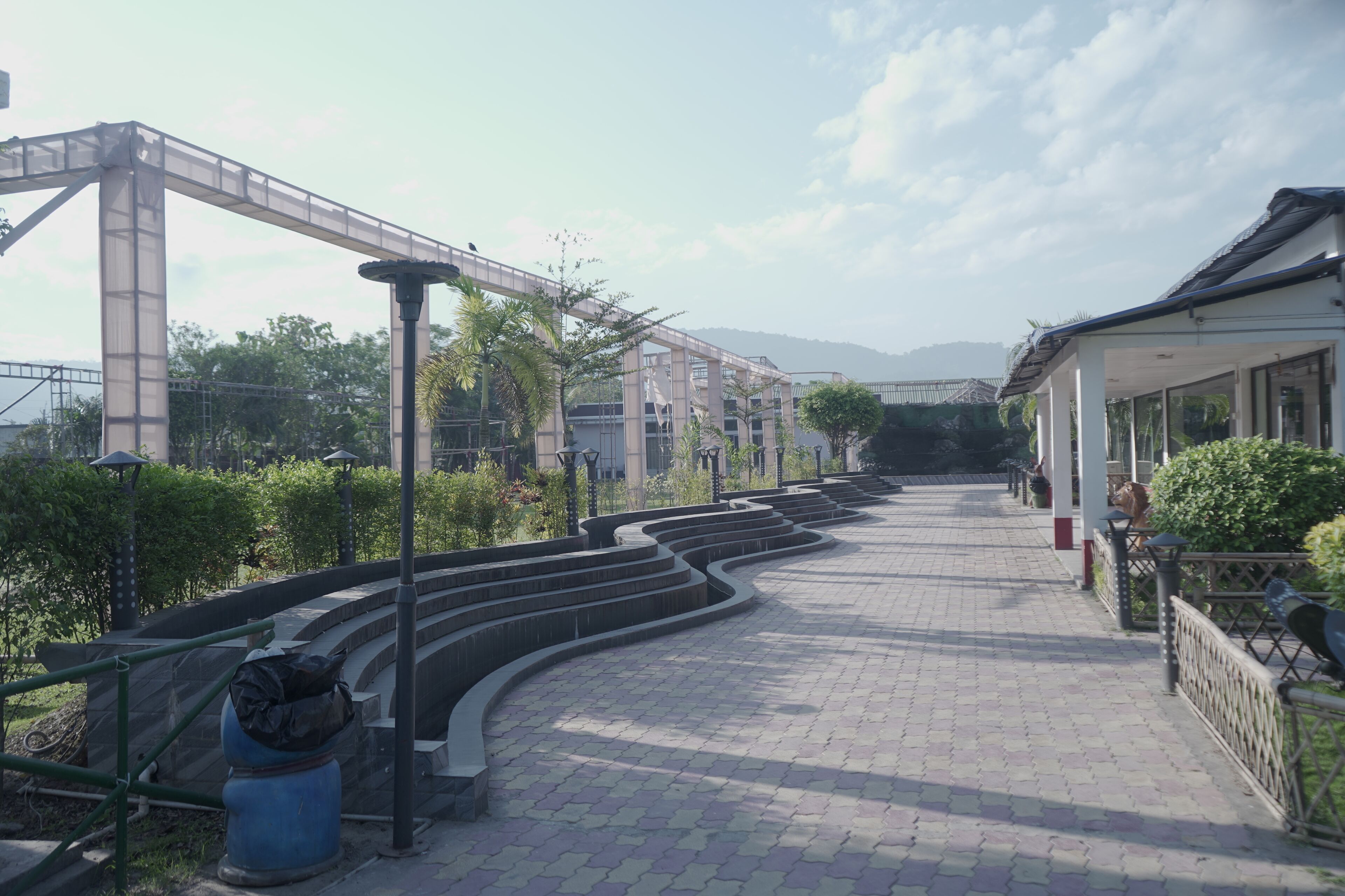 A pathway with steps leading to a building, surrounded by greenery and a clear sky.