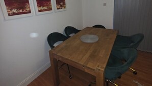 Ein Essbereich mit einem Holztisch, vier Stühlen und drei Bildern an der Wand.