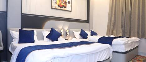 A hotel room with a large bed, two bedside tables, a headboard, a painting on the wall, and a curtain.