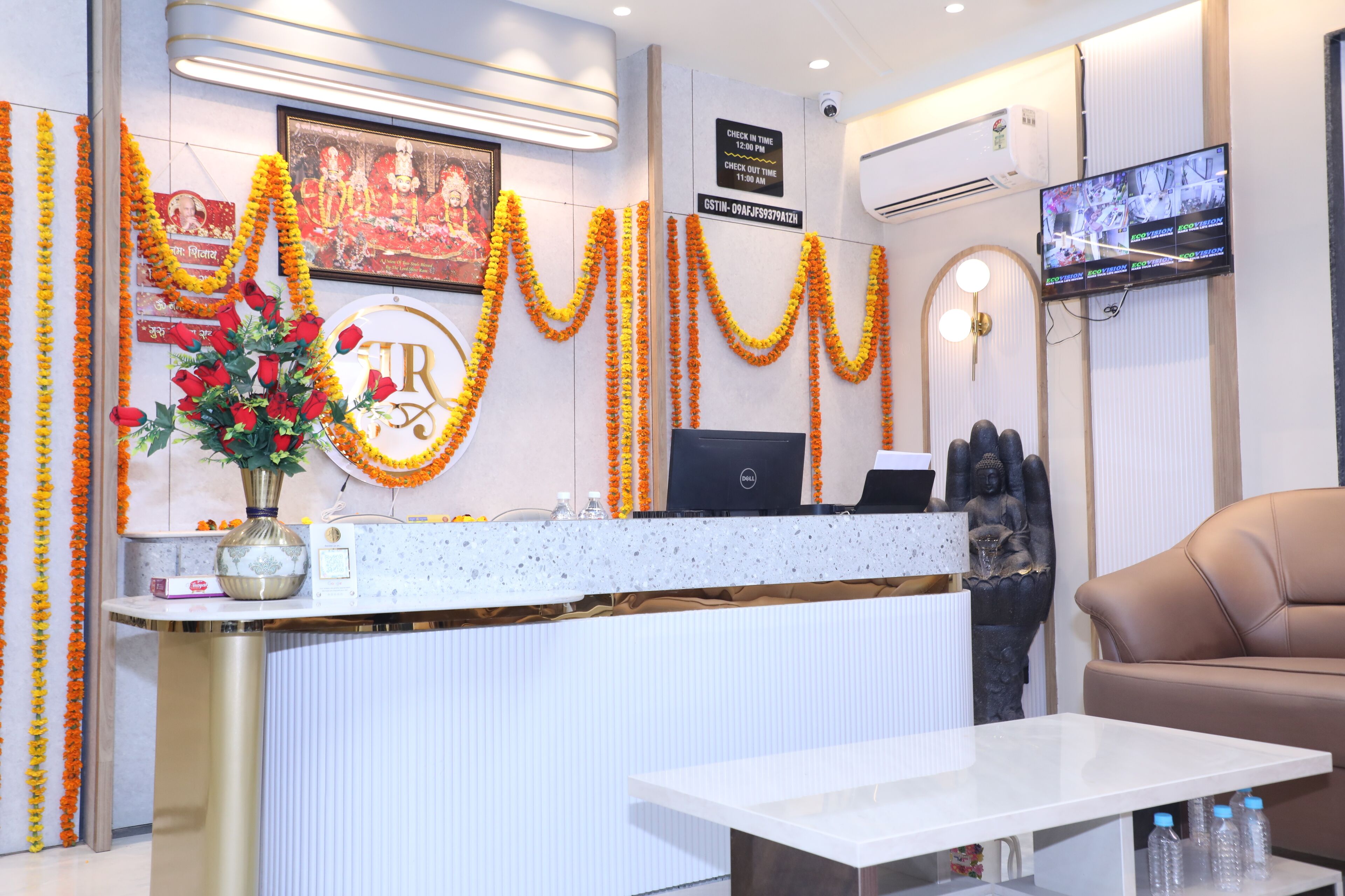 A reception area with a counter, a computer, a statue, and a television.