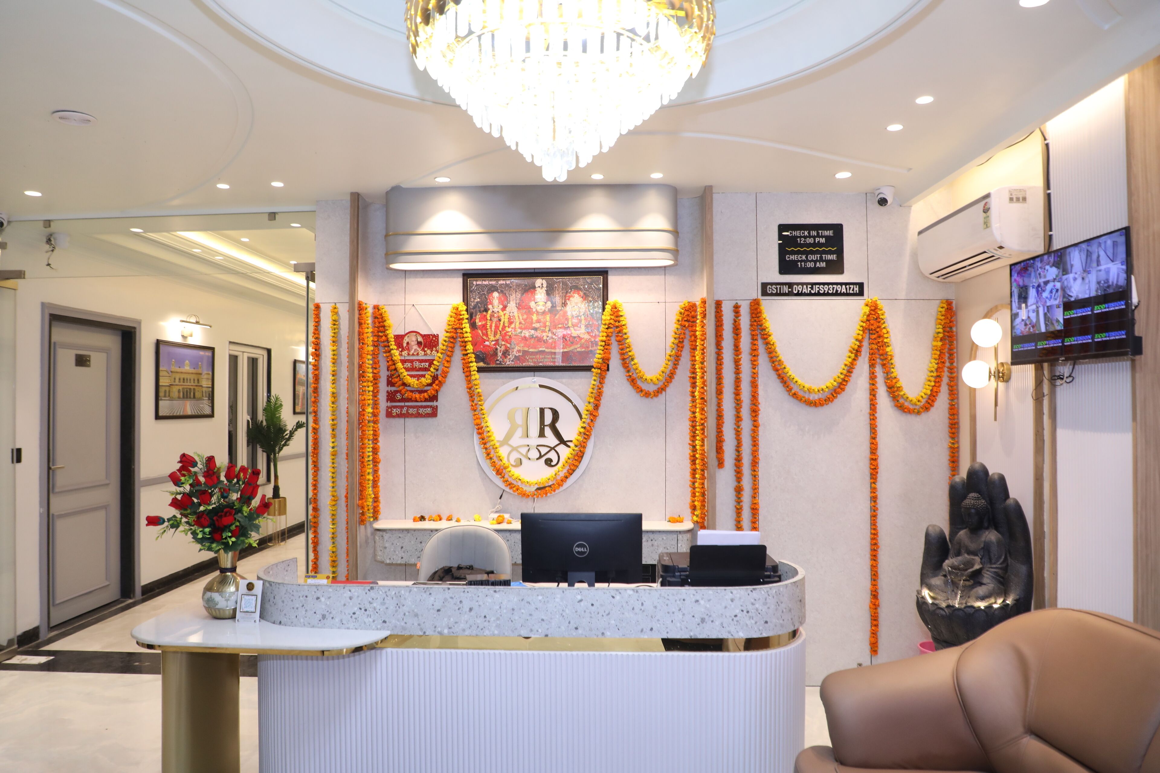 A reception area with a desk, computer, and a Buddha statue.