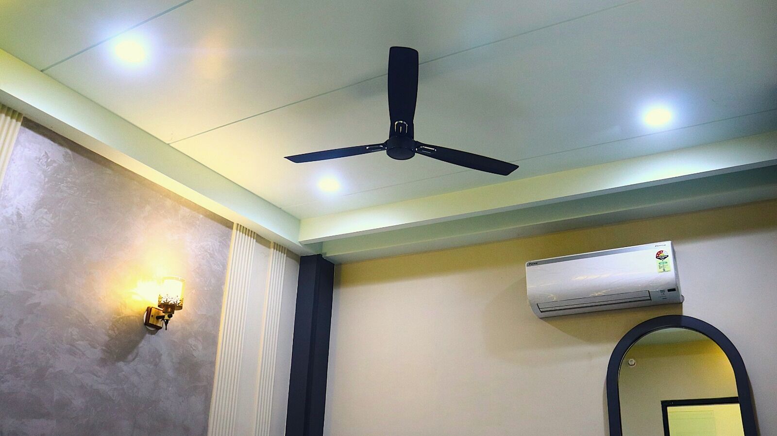 A ceiling fan, recessed lighting, a wall-mounted air conditioner, and a mirror.