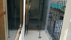 Un couloir étroit avec un portail en métal, une petite marche menant à une porte, et une vue sur l’extérieur à travers le portail.