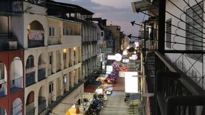 Une rue étroite bordée d’immeubles à plusieurs étages, dont certains sont dotés de balcons et d’enseignes.