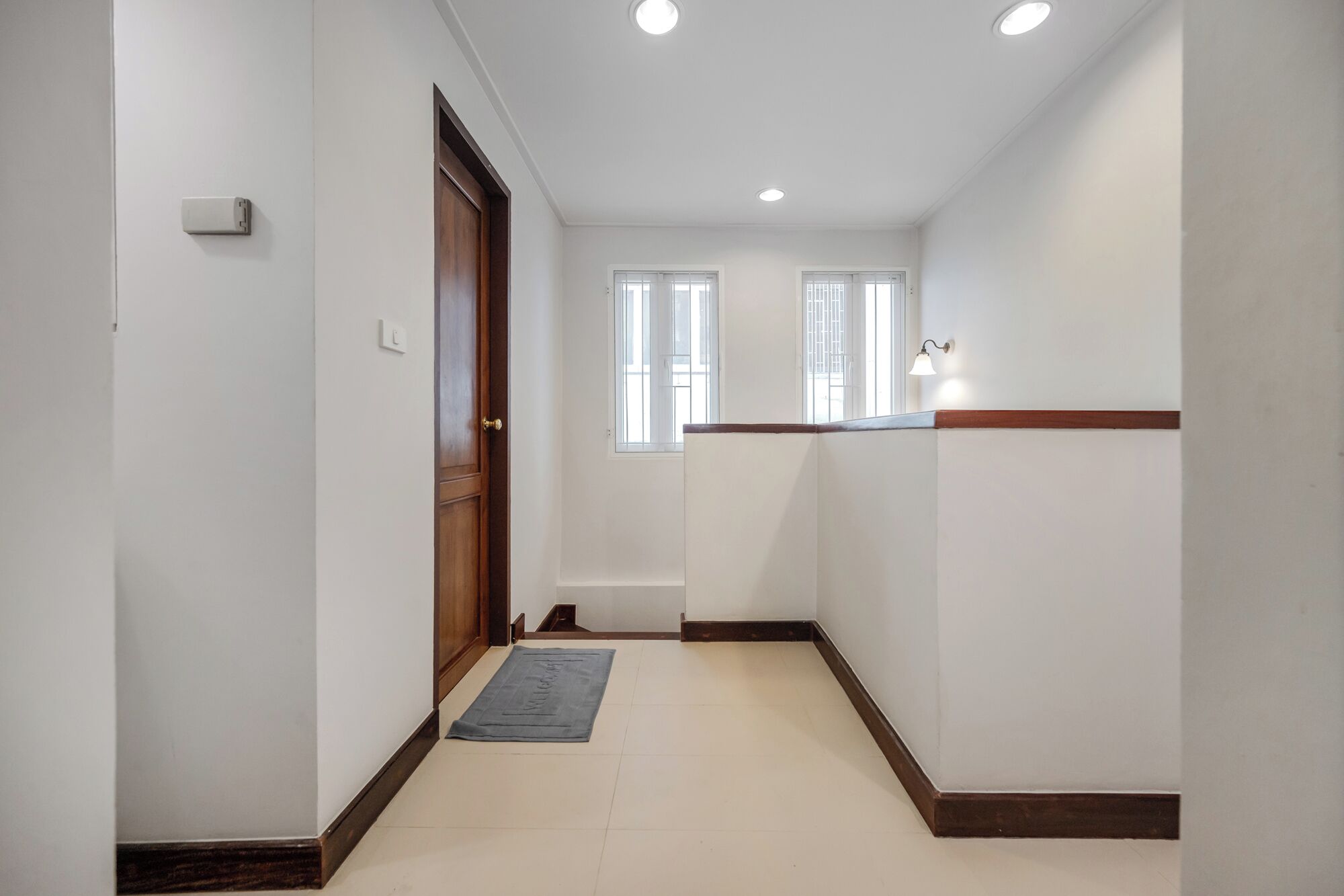 A hallway with a wooden door, a light switch, and a window with a view.