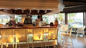Zona de bar con camarero, barra y sillas de mimbre.
