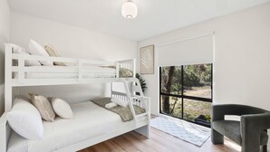 A bunk bed room with a view of a natural landscape through large windows.