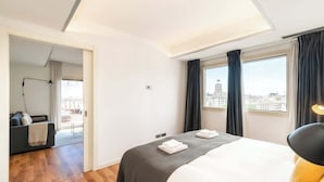 A modern hotel room with a large bed, a view of the city, and a balcony with a sofa. - Placa Catalunya gran duplex (Barcelona)