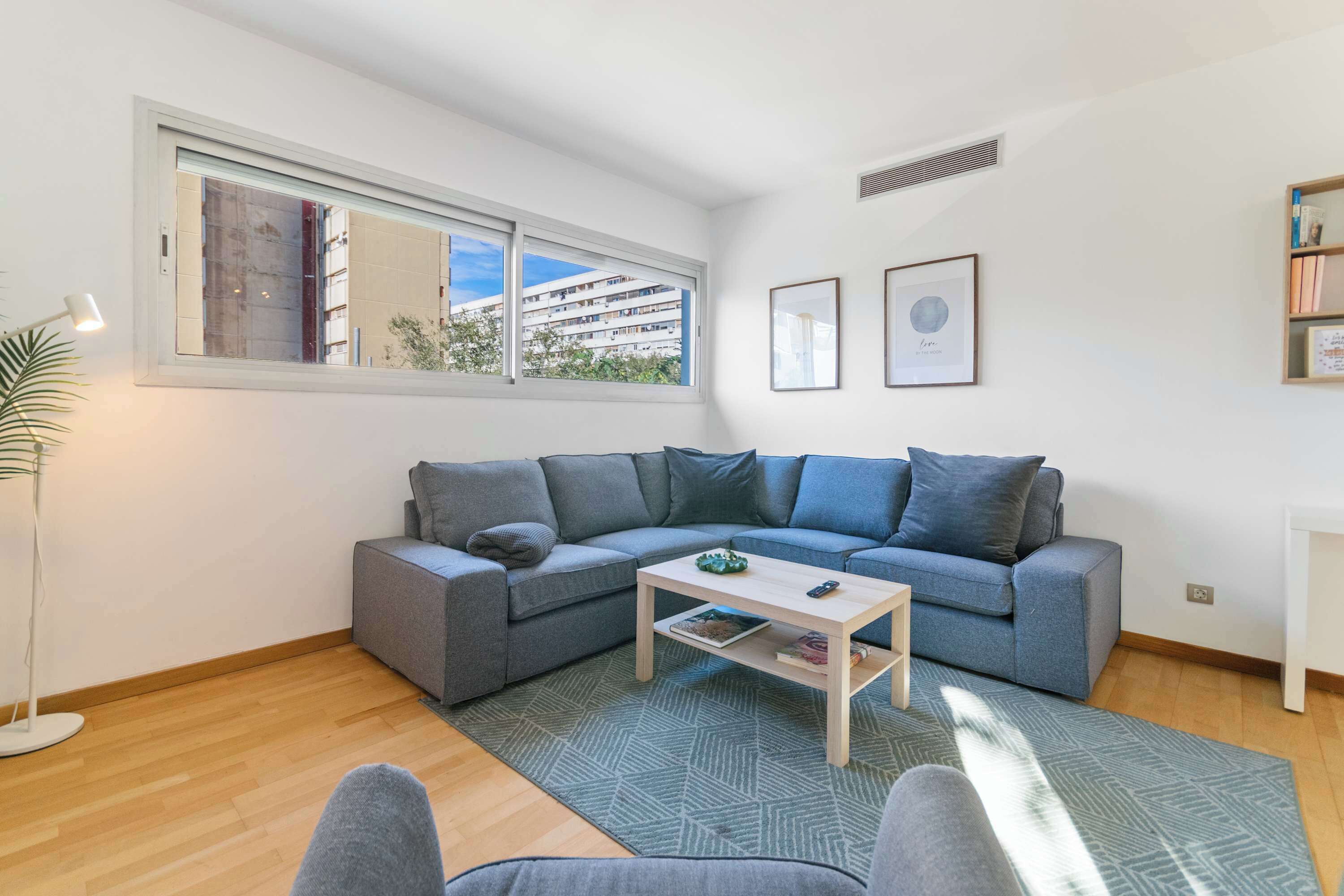 A modern living room with a grey sectional sofa, a wooden coffee table, and a patterned rug.