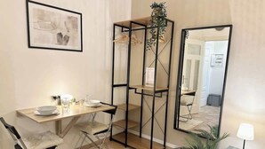 Un espace de vie compact comprenant une table à manger, deux chaises, un miroir et une petite plante.