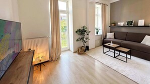 Un salon moderne avec un canapé, une table basse, un radiateur et une grande fenêtre avec des rideaux.