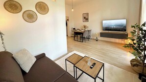 Un salon moderne avec un canapé, une table basse et un téléviseur fixé au mur.