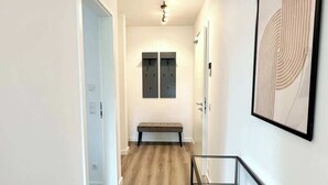 A hallway with a wooden floor, a bench, and a framed artwork on the wall.
