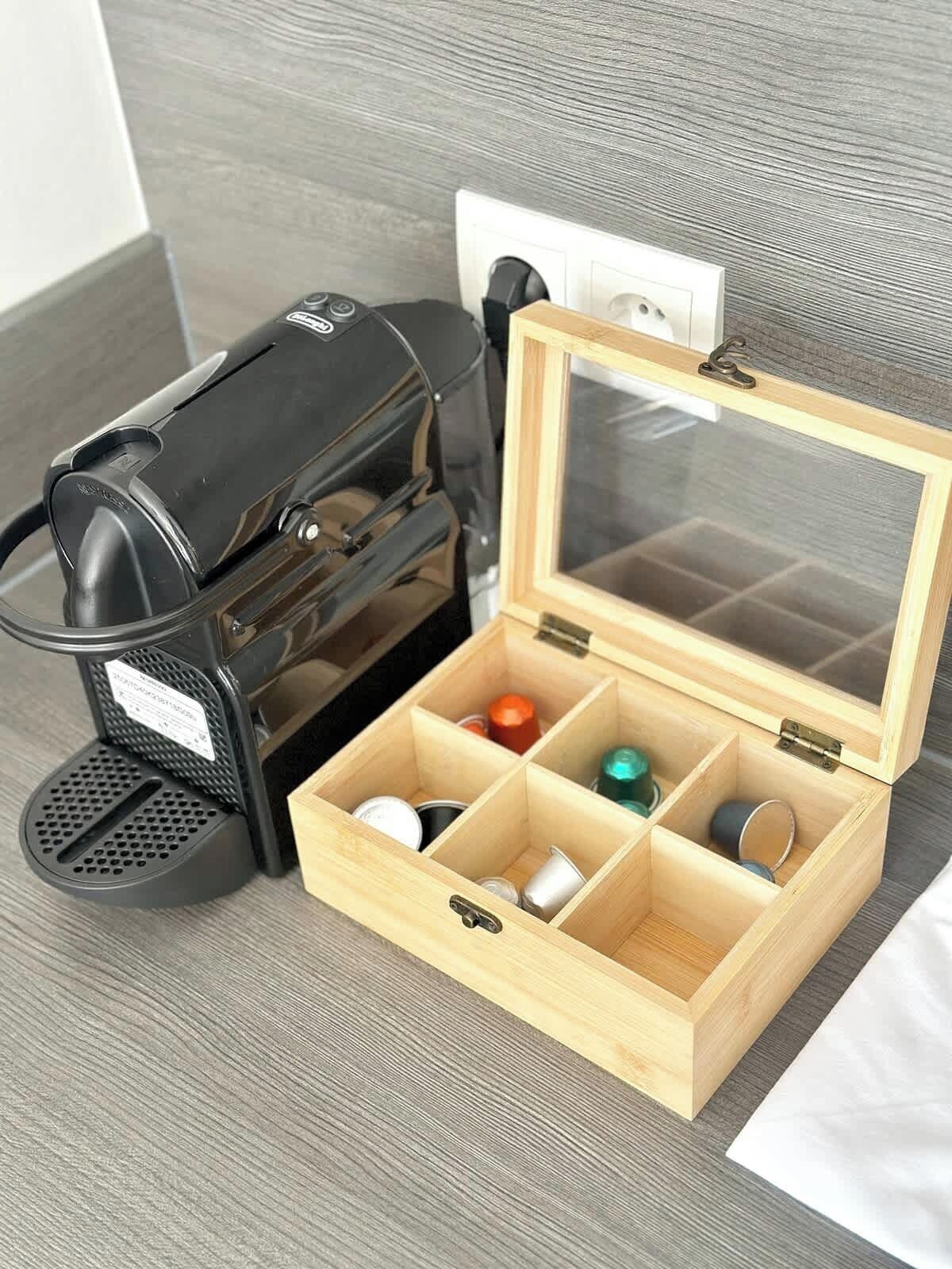 A coffee maker and a wooden box with compartments containing various items.