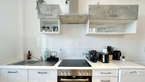 Una cocina moderna con horno empotrado, lavavajillas y cafetera sobre la encimera.