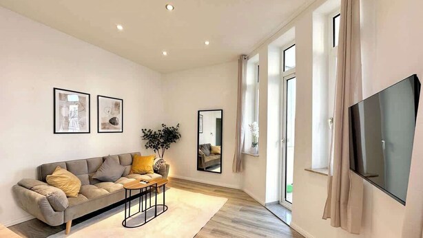 Una sala de estar moderna con sofá, mesa de centro y televisor de pantalla plana.
