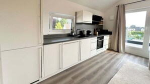 Una cocina moderna con armarios blancos, encimera negra y un ventanal amplio.