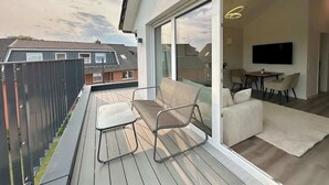 Un apartamento moderno con balcón, sofá, mesa y televisor en la sala.