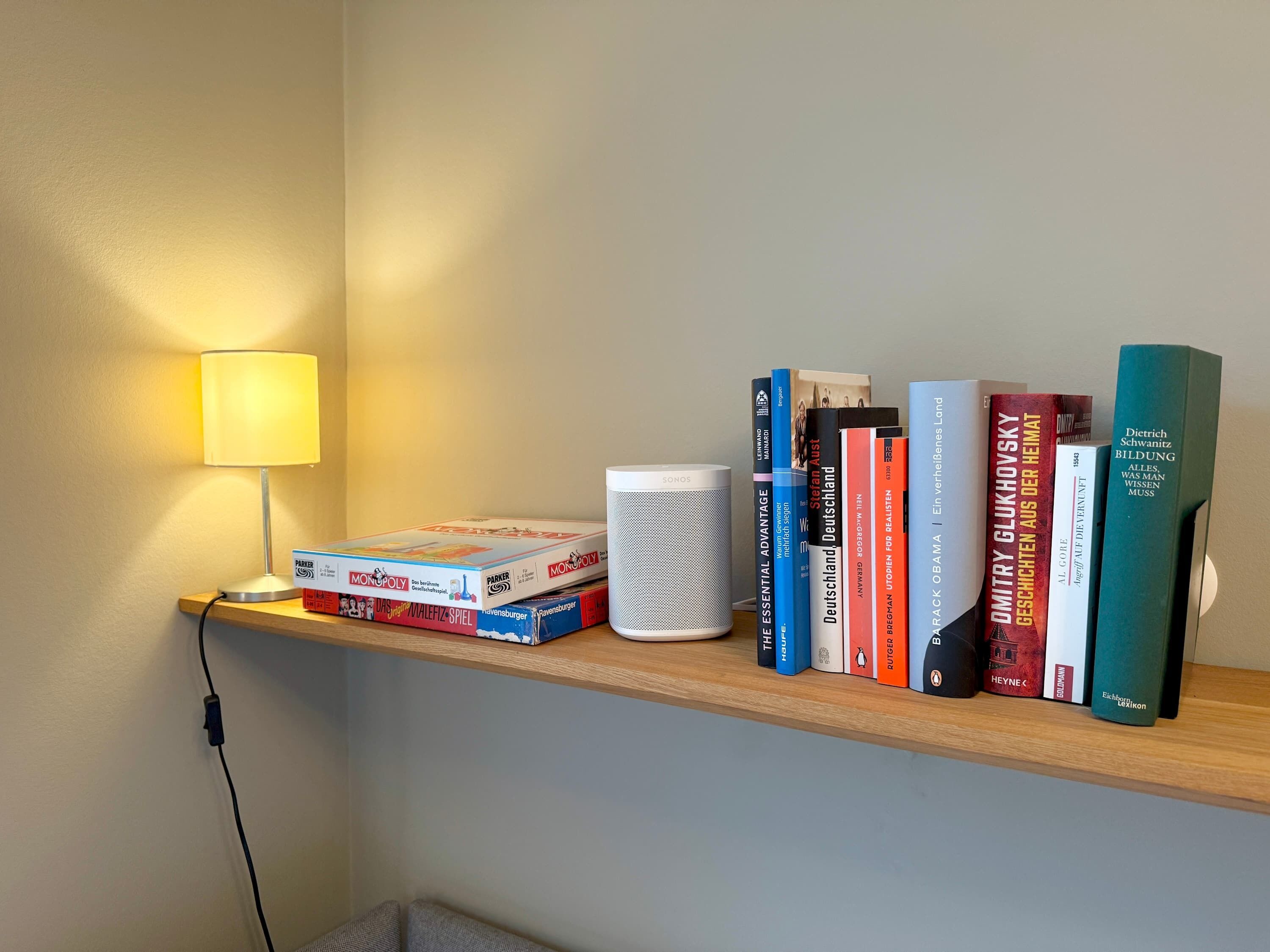 Een plank met boeken, een lamp en een speaker.