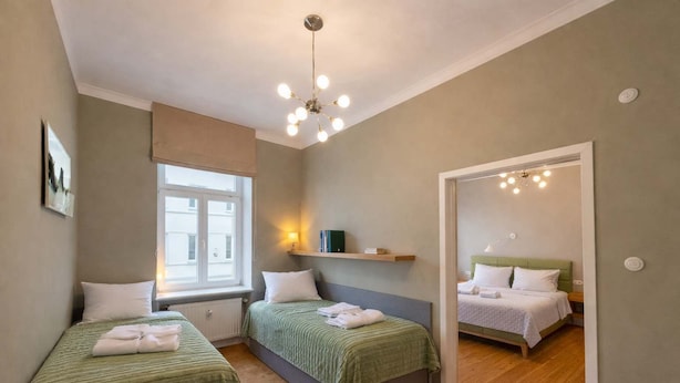 Ein Schlafzimmer mit zwei Betten, einem Fenster, einem Spiegel und einer Deckenleuchte.