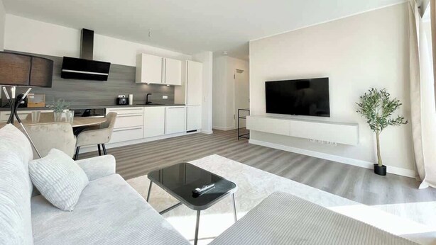 Ein modernes Wohnzimmer mit einer Couch, einem Couchtisch und einem an der Wand befestigten Flachbildfernseher.