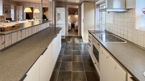 Una cucina moderna con pavimento in piastrelle scure, lavastoviglie integrata e cappa aspirante in acciaio inossidabile.