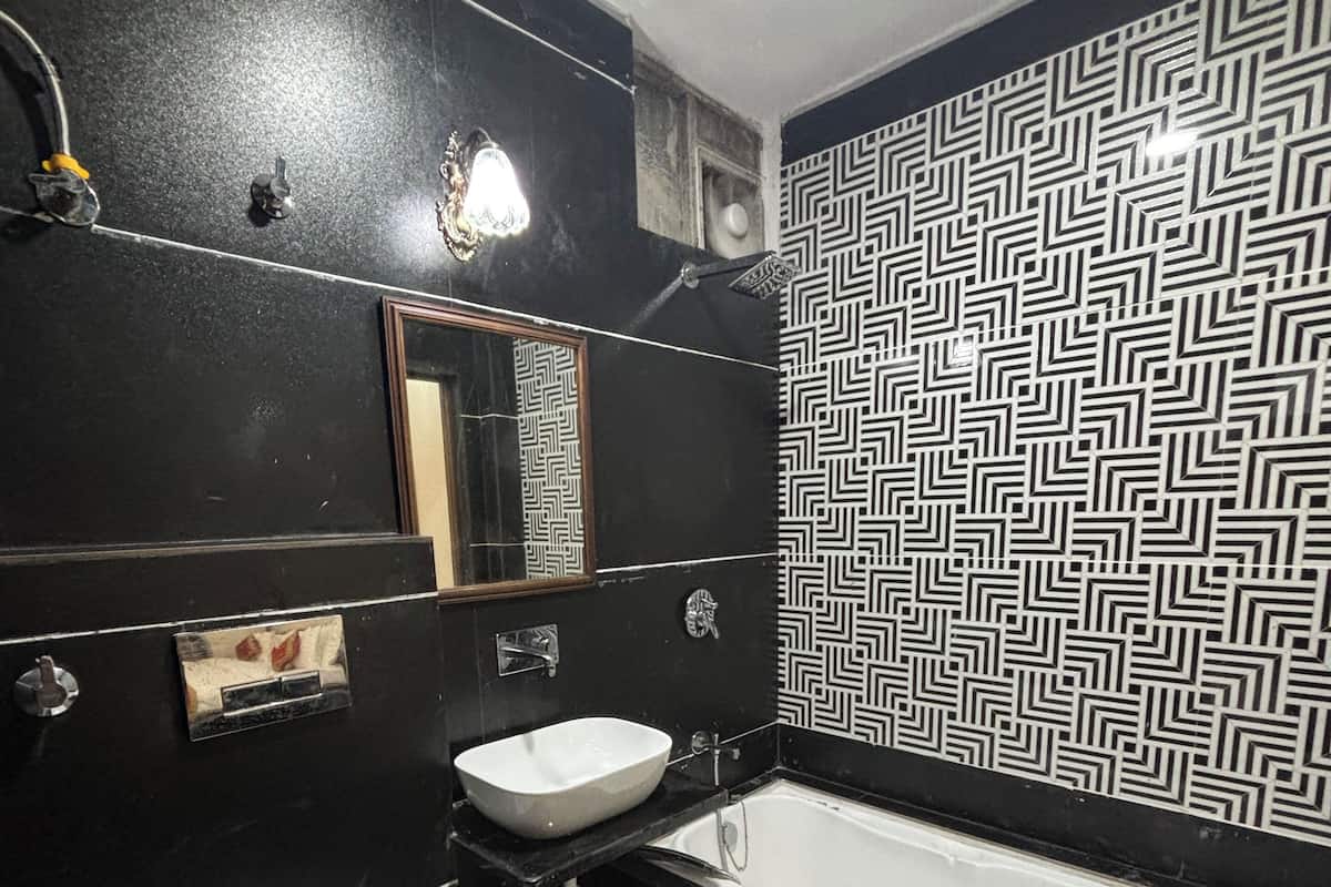 A bathroom with a black and white patterned wall, a white sink, a white toilet, and a bathtub.