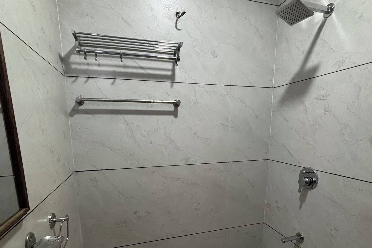 A bathroom with a white sink, a shower, and a towel rack.