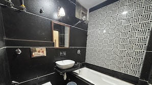 A bathroom with a black and white patterned wall, a white sink, a toilet, and a bathtub. - Hotel Royale Plazo (Jodhpur)