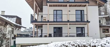 A two-story building with balconies, large windows, and a sloped roof.