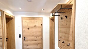 Un couloir avec des portes en bois, un canapé et un porte-manteau fixé au mur.