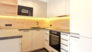 Une cuisine moderne avec des meubles blancs, un four encastré et un four à micro-ondes.