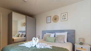A neatly arranged bedroom with a large bed, a bedside table, a mirror, and wall decorations. - Cosy apartment for 6 people with A/C, WIFI, TV and balcony (Bruges)