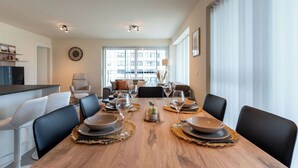 A modern dining room with a wooden table set for six, surrounded by chairs. - Cosy apartment for 6 people with A/C, WIFI, TV and balcony (Bruges)