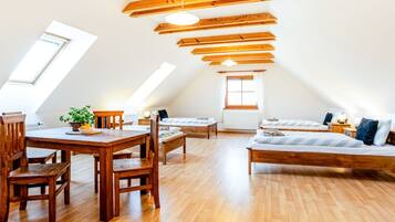 Spazioso loft con soffitto alto, travi in legno, angolo pranzo con tavolo e sedie, divano e un letto.