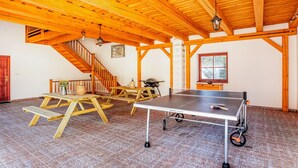 A spacious room with a ping pong table, wooden benches, and a staircase. - Beautiful private villa for 10 people with WIFI, private pool, terrace and pets allowed (Lesní Chalupy)