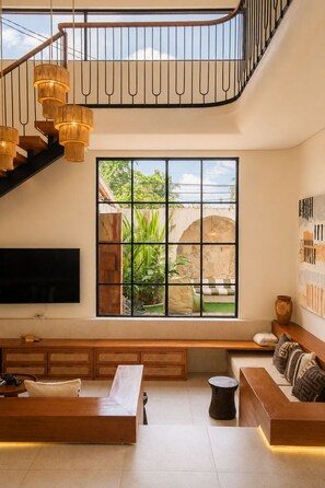 Un salon moderne doté d’une grande fenêtre, d’un escalier et d’un téléviseur à écran plat.