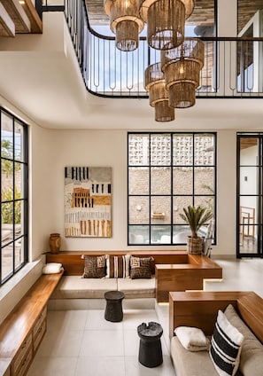 A spacious living area with a high ceiling, a large window with a view, a modern art piece, and a seating area with a bench and a sofa. - Chic 4-br Villa in Central Seminyak, Beach 10 min (Seminyak)