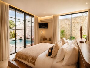 A bedroom with a large bed, a TV mounted on the wall, and a view of a pool and outdoor area. - Chic 4-br Villa in Central Seminyak, Beach 10 min (Seminyak)