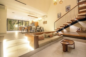 Ein geräumiger Wohnbereich mit Sofa, Couchtisch und einer Treppe.