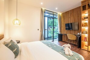 A hotel room with a bed, a desk, a TV, and a view of the outdoors. - Exquisite 6-bedroom Retreat, Moments to Beach (Seminyak)