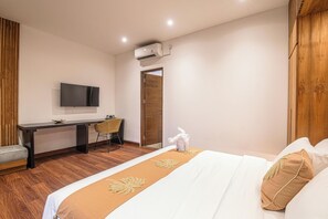 Une chambre d’hôtel équipée d’un lit, d’un bureau, d’une chaise, d’une télévision et d’un appareil de climatisation.