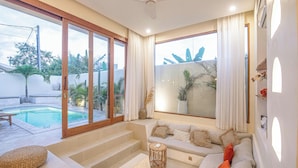A modern living room with a sofa, a small table, and a staircase leading to a balcony. - Chic Villa Living, Hidden Serenity of Canggu (Canggu)