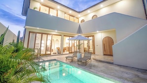 A modern two-story house with a swimming pool, outdoor seating, and a well-lit interior. - Chic Villa Living, Hidden Serenity of Canggu (Canggu)
