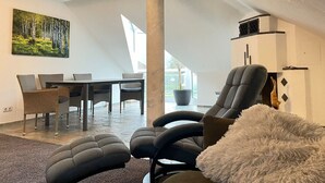 Una sala de estar moderna con comedor, que presenta un columno grande, un sofá y un cuadro de un bosque.